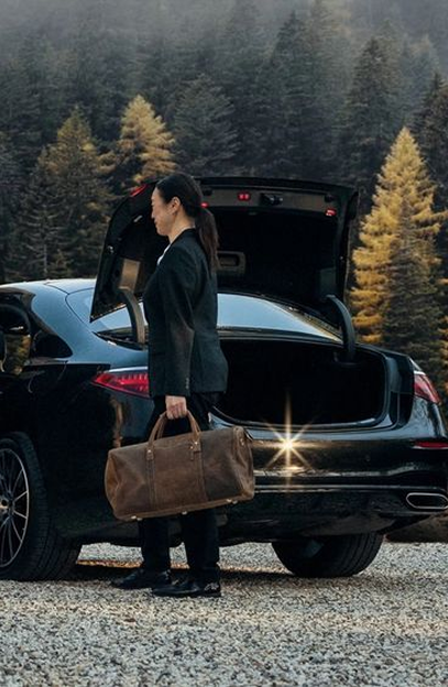 Female chauffeur driver carrying bag from limo trunk