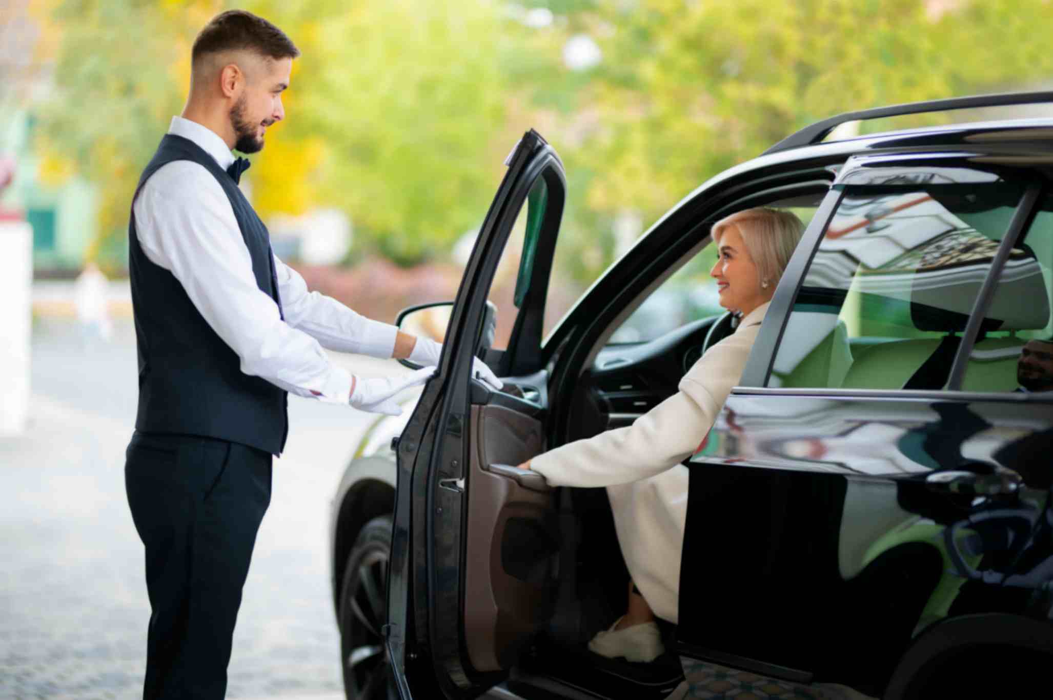 Benefits hiring chauffeured services chauffeur driver helping a woman park the limo car
